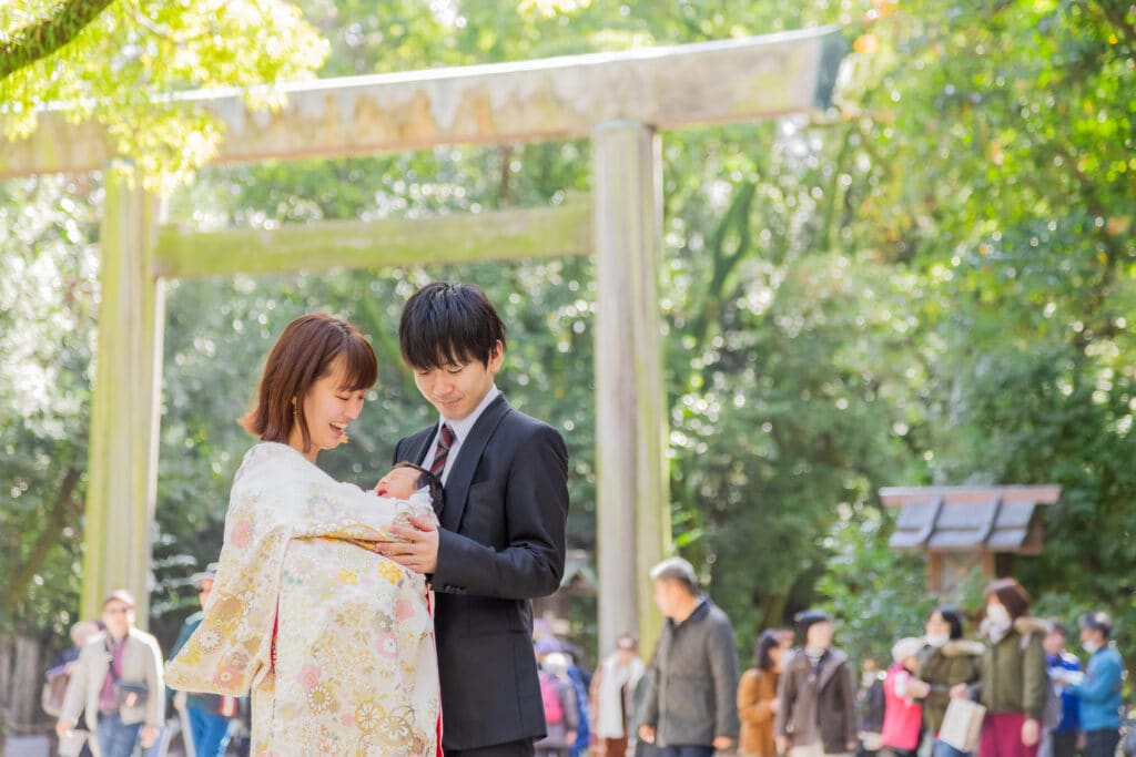 熱田神宮の鳥居の前で、お祝い着の赤ちゃんを抱いたご家族