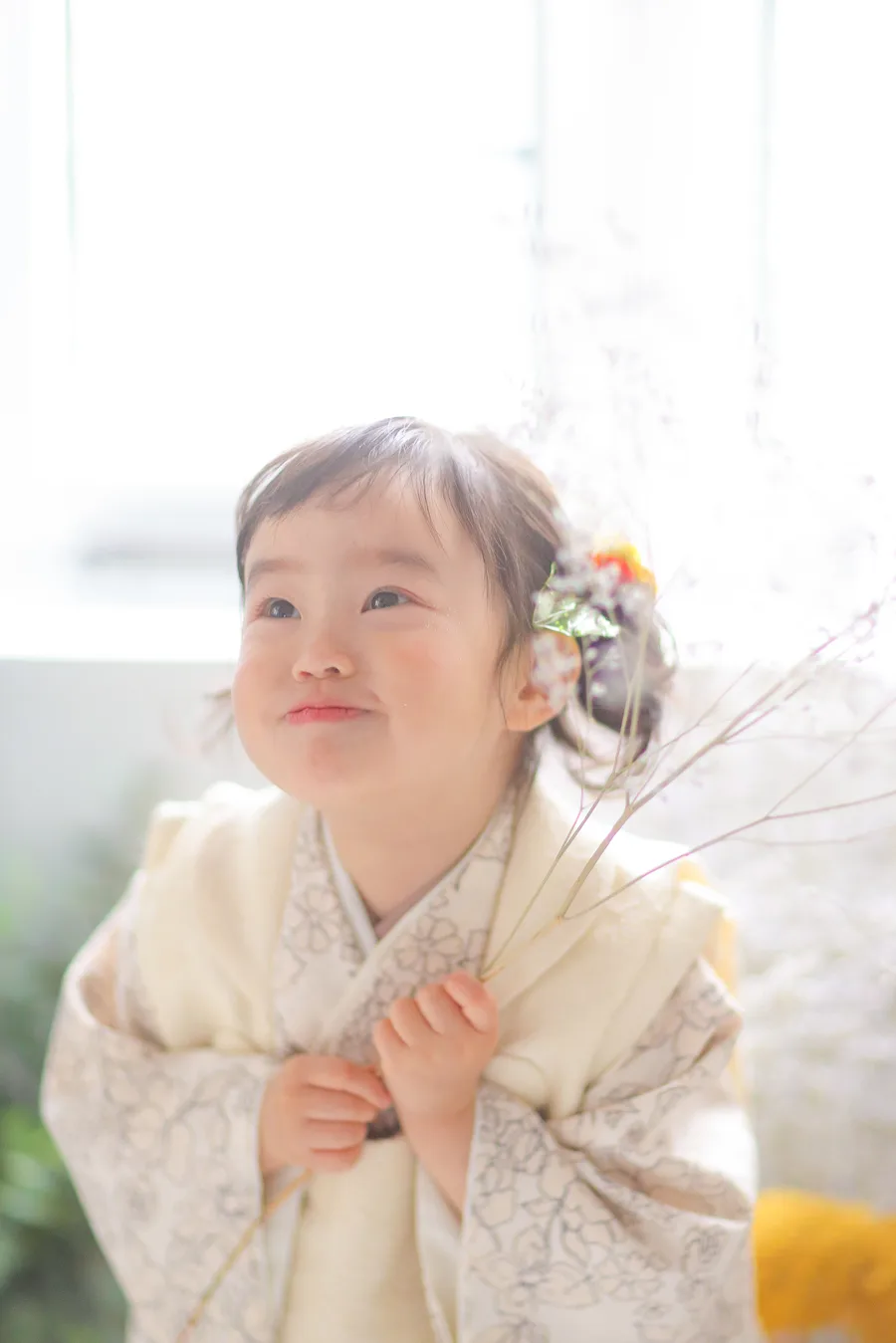 生成りの被布を着て見上げる3歳の女の子