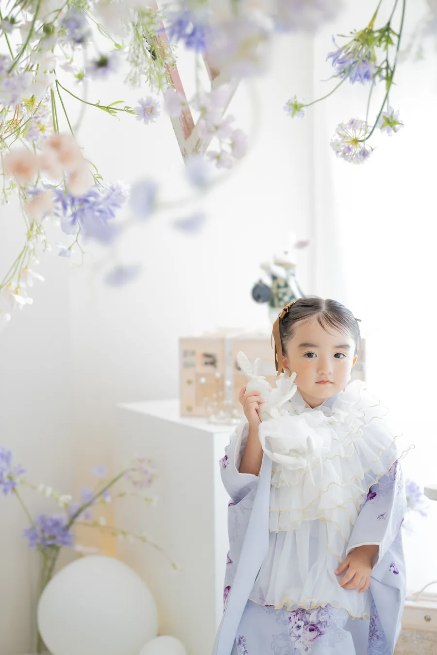 花に囲まれたスタジオに立つ3歳の女の子