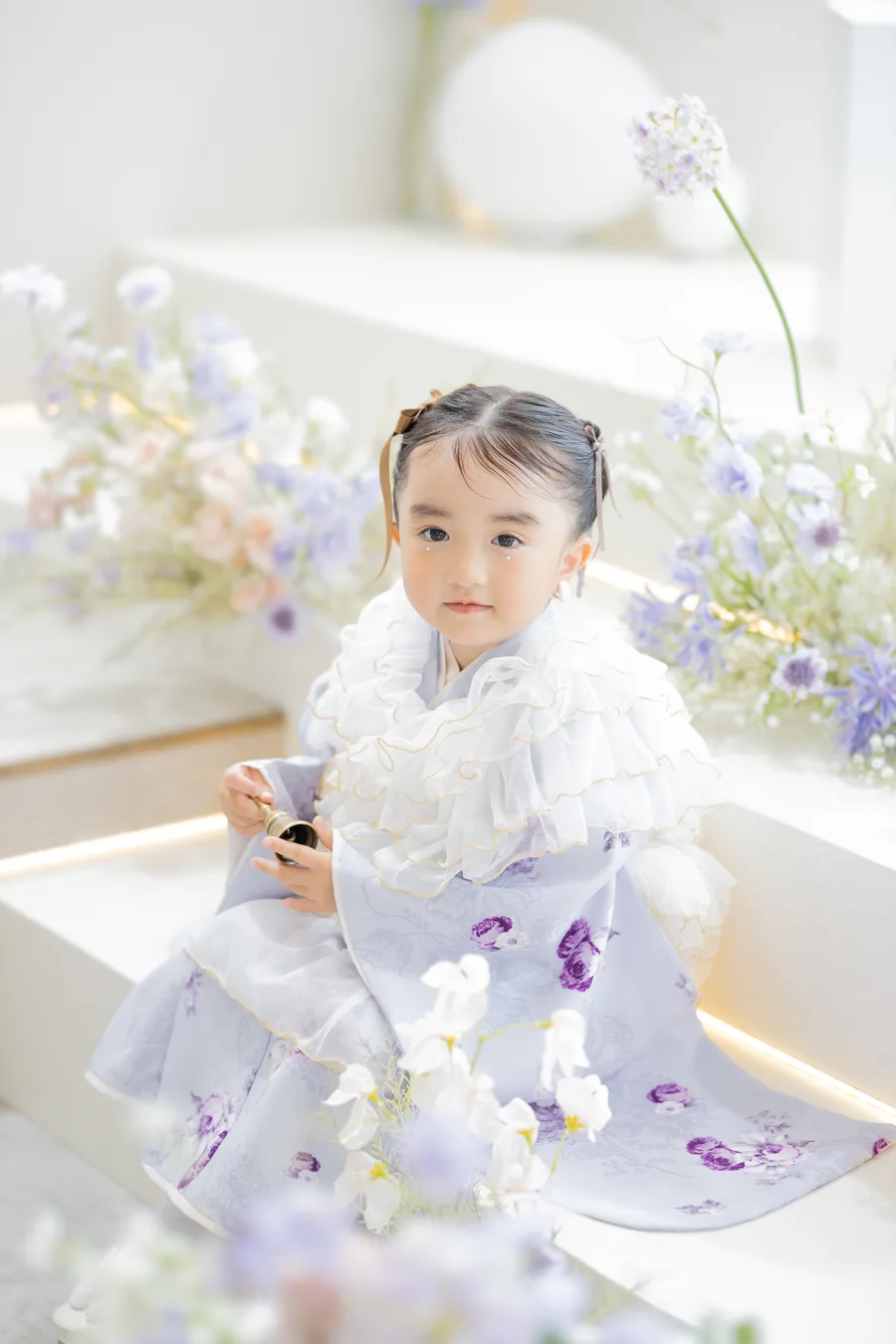 薄紫の被布を着て階段に座る3歳の女の子