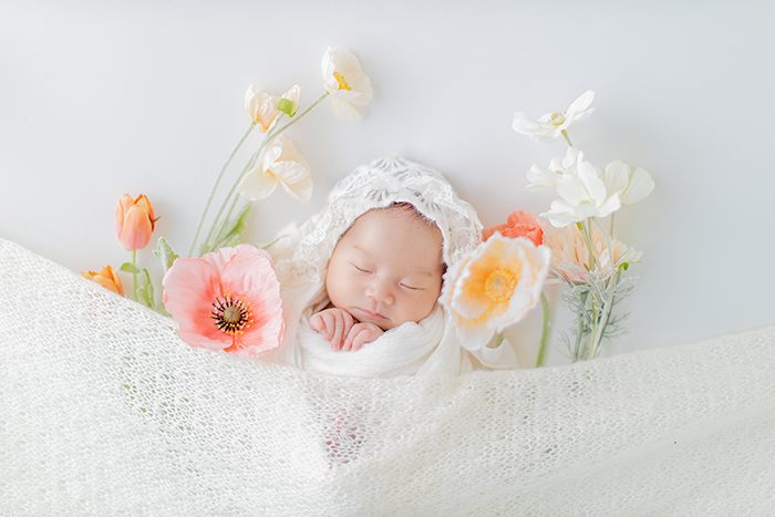 花に囲まれておくるみに包まれた新生児
