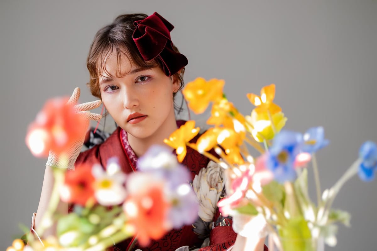 赤い振袖にベロアのリボンを合わせ、花越しに寄って撮影した成人式の前撮り写真