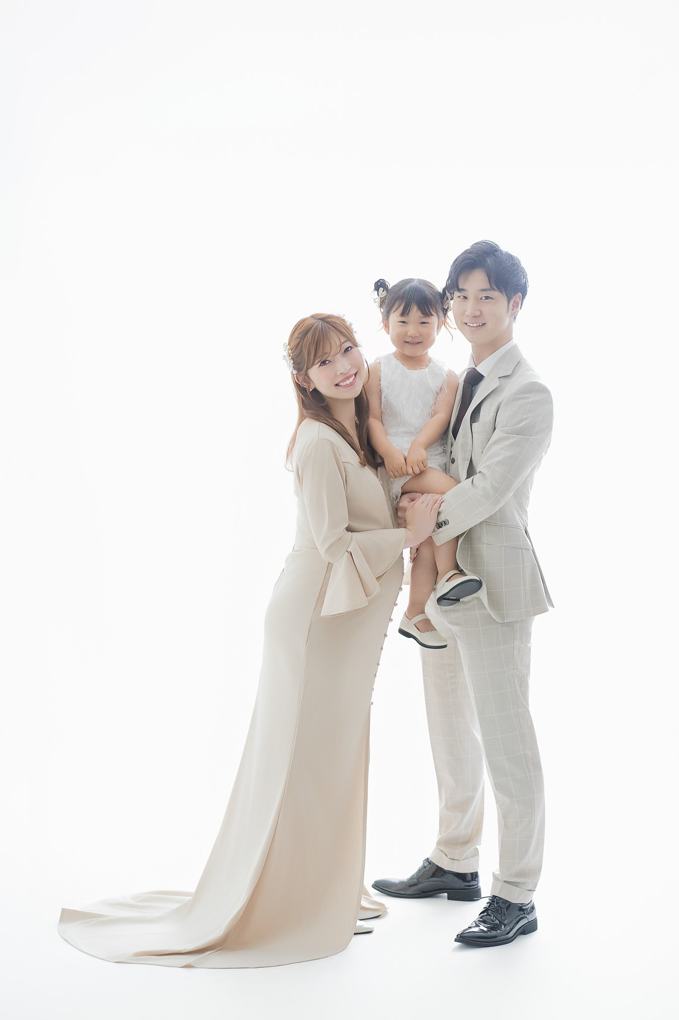 上の子を抱き上げて並ぶ、ご夫婦とお子さまの家族写真