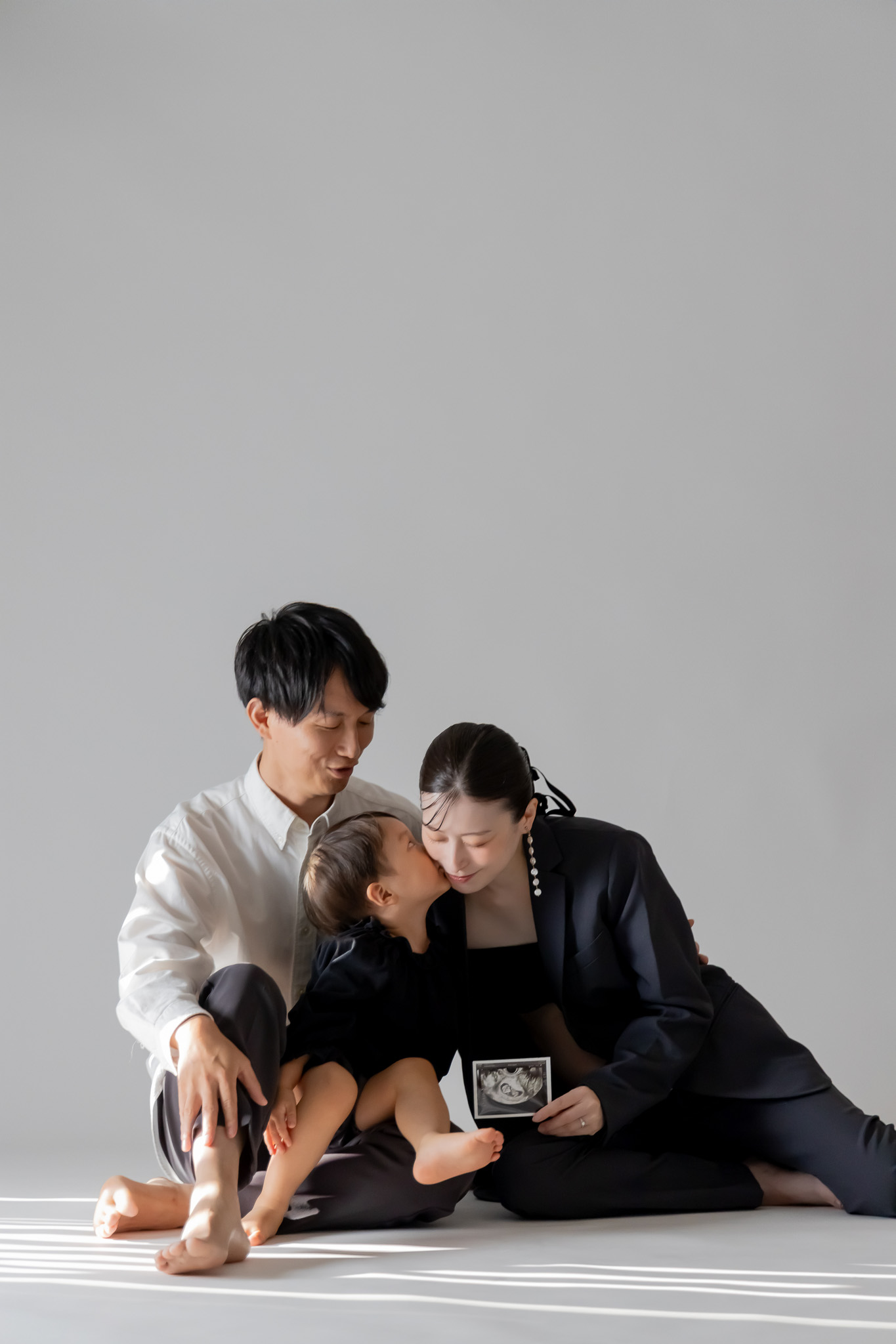 床に座り、上の子とエコー写真を囲むご家族