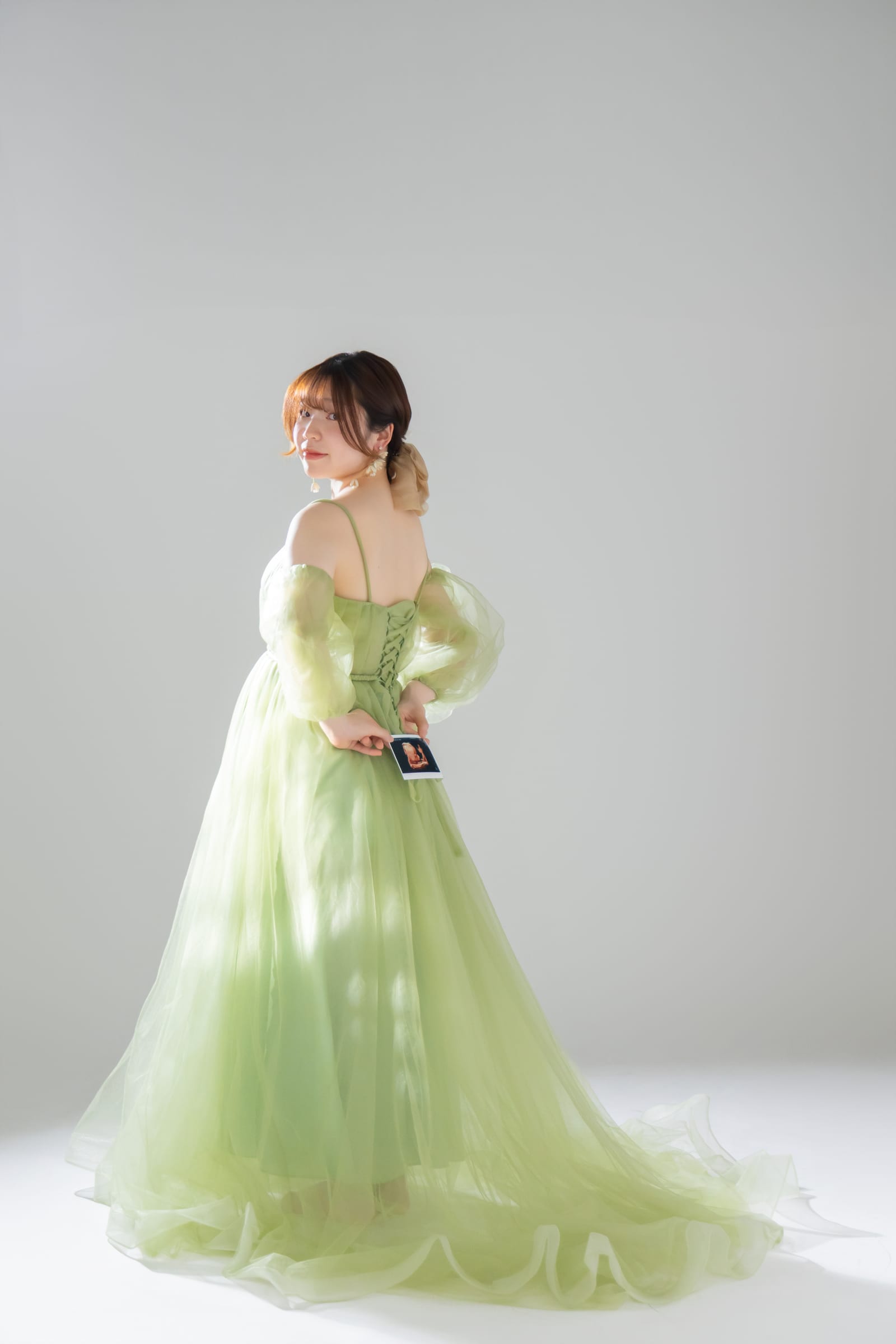 グリーンのドレスで背を向け、エコー写真を持つ後ろ姿