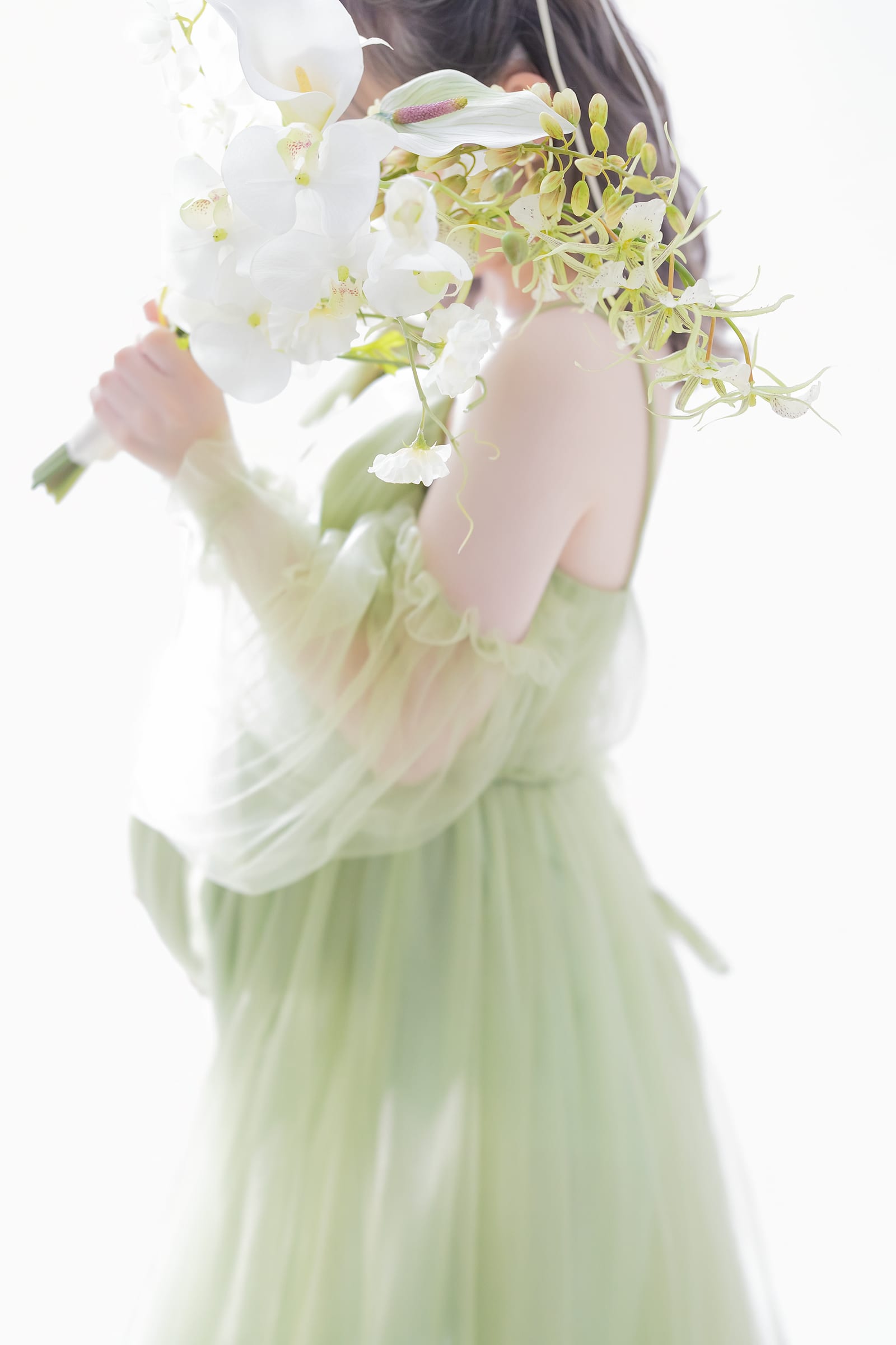 白い花を抱え、グリーンのドレスをまとった横姿